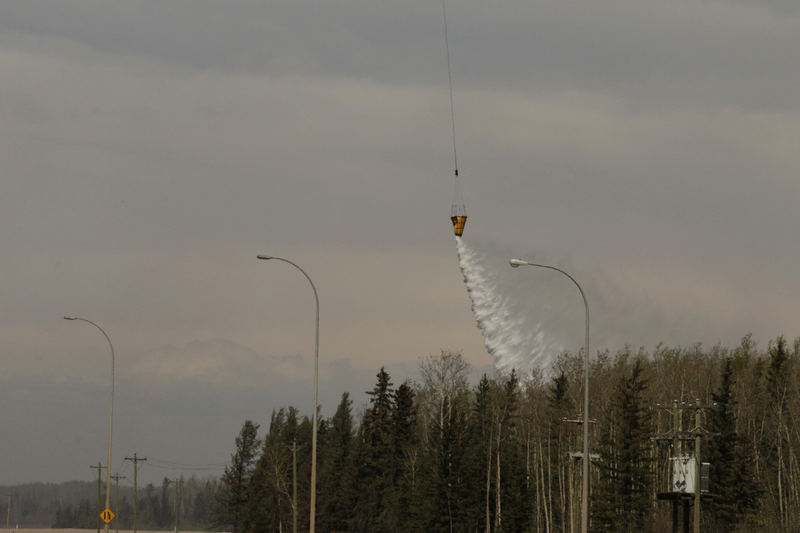 Water is released from a helicopter hovering over a wildfire near near Fort McMurray, Alberta in 2016. Photo Credit: AP/Rachel La Corte